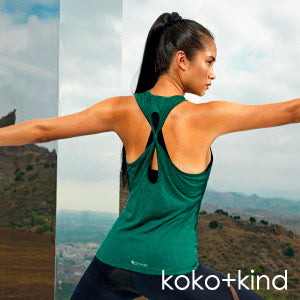Female doing warrior pose in yoga wearing green koko+kind yoga vest